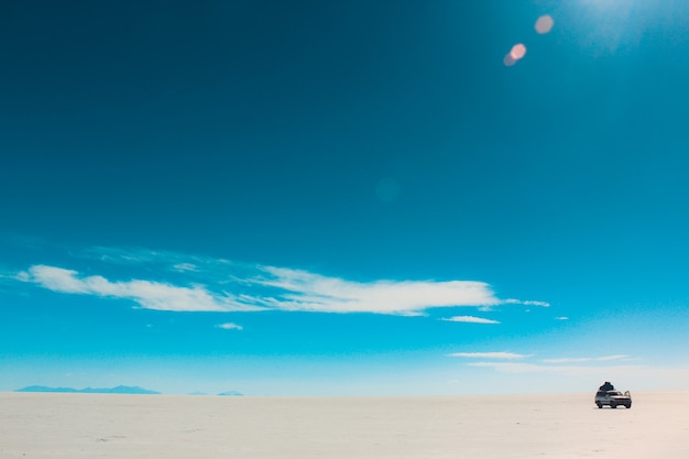 Beautiful shot of the sky with faded clouds on a bright day with a car in the desert