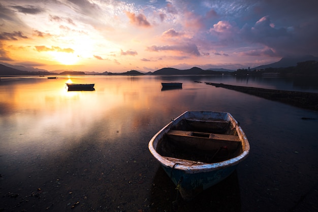 Free photo beautiful shot of a small lake with a wooden rowboat in focus and amazing clouds in the sky