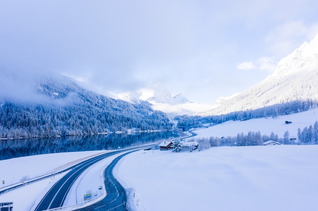 Beautiful shot of snow-covered mountains, wooden cottages and a lake reflecting the trees