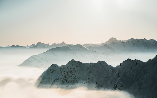 澄んだ空と雲の上の雪に覆われた山のてっぺんの美しいショット