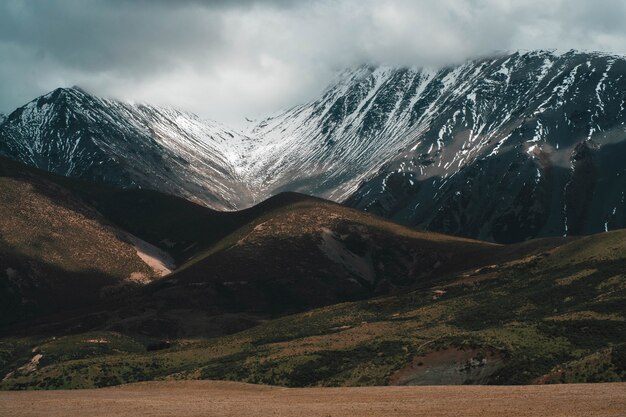 Free Photo Beautiful Shot Of Snowy Rocky Mountains And Hills Under A Misty Cloudy Sky