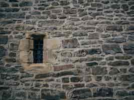 Foto gratuita bello colpo di una vecchia struttura del mattone di pietra con una piccola finestra bloccata