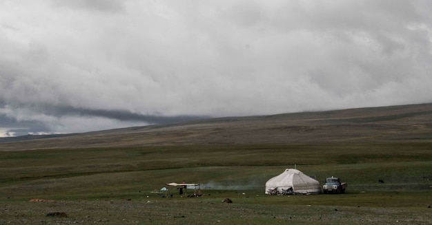 Красивый снимок палатки на травянистом поле с толстым слоем облаков в небе в прохладный день