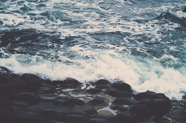 Beautiful shot of the waves of the ocean crashing on the stones in the shore