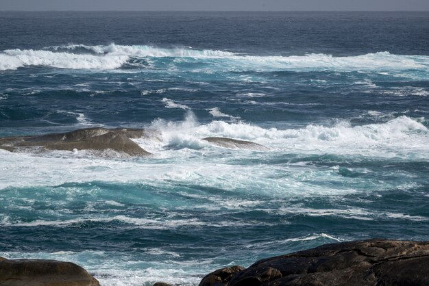 Beautiful shot of the wavy ocean with some stones in the water