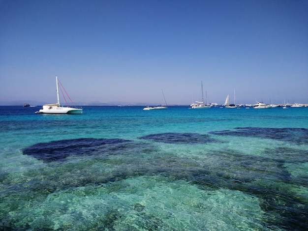 Beautiful shot of white boats in coast next to Formentera, Spain