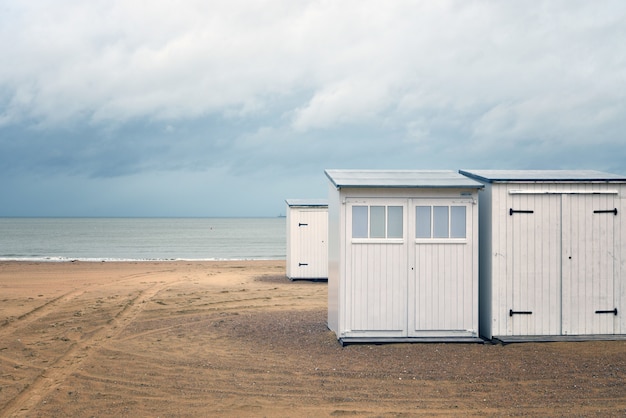 Free photo beautiful shot of white small rooms on a beach shore near the water under a cloudy sky