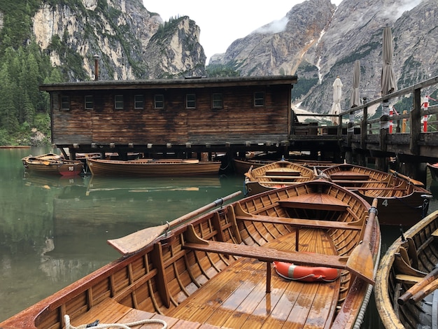 Free photo beautiful shot of wooden boats on braies lake, on background of dolomites, trentino-alto adige,   pa