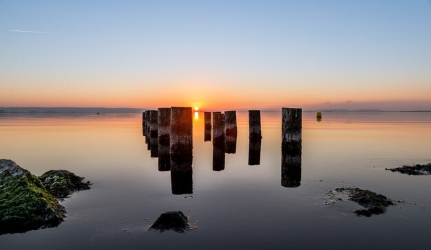 日没時に水の体に使い古された桟橋柱の美しいショット。壁紙に最適