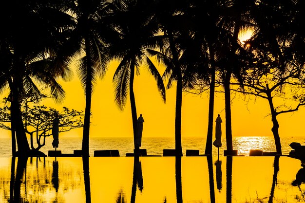 Beautiful Silhouette coconut palm tree on sky around swimming pool in hotel resort neary sea ocean b