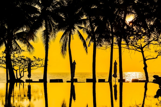Beautiful Silhouette coconut palm tree on sky around swimming pool in hotel resort neary sea ocean b