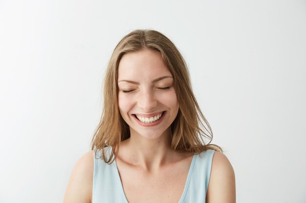 Beautiful sincere happy cheerful girl smiling laughing with closed eyes .