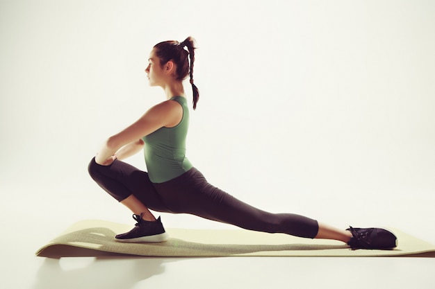 Beautiful slim brunette doing some stretching exercises in a gym