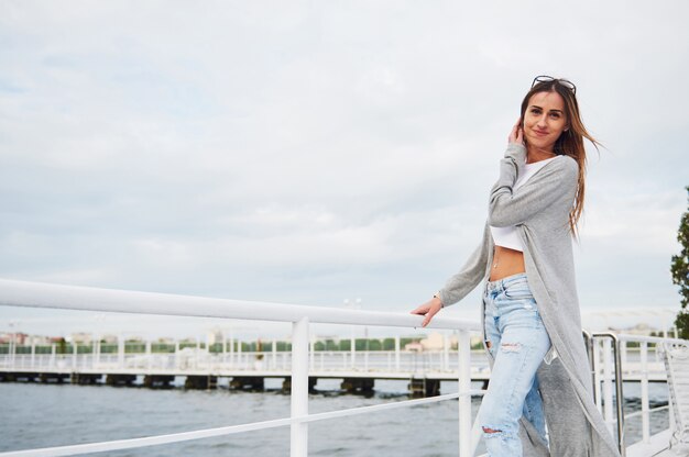 Beautiful smile girl standing on a pier near the water.