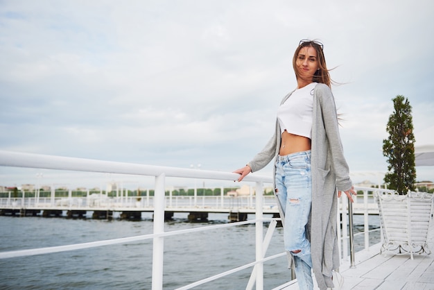 Beautiful smile girl standing on a pier near the water.