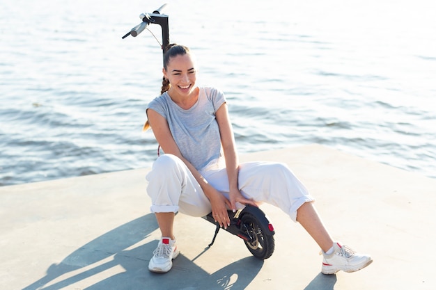 Free photo beautiful smiley woman sitting on scooter