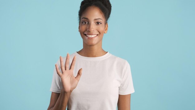 Beautiful smiling African American girl happily waving hello on camera over colorful background. Greeting expression