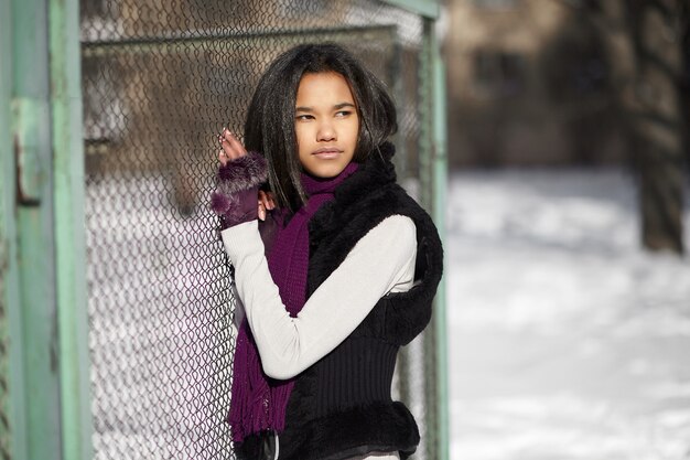 Beautiful smiling american girl sitting in snow outdoors playing with snow