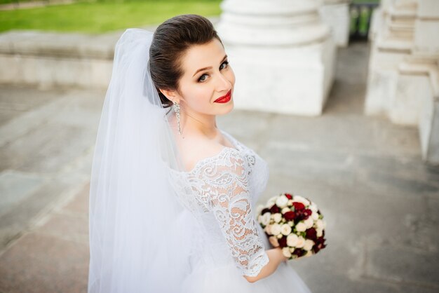 Beautiful smiling bride portrait near architecture with flowers