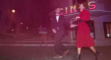 Free photo beautiful smiling lady walking with young positive guy on street in evening