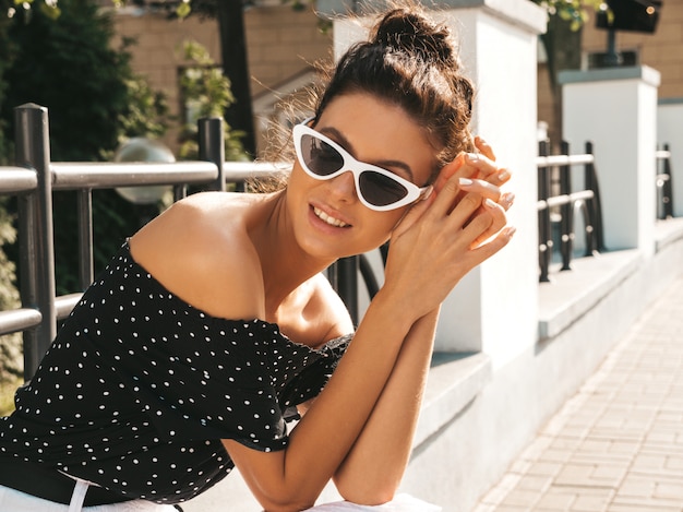 Free photo beautiful smiling model dressed in elegant summer clothes.sexy carefree girl sitting in the street.trendy modern businesswoman in sunglasses having fun