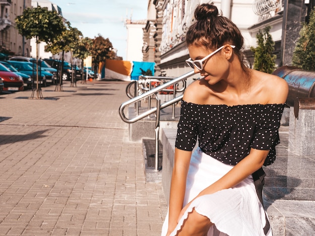 Free photo beautiful smiling model dressed in elegant summer clothes.sexy carefree girl sitting in the street.trendy modern businesswoman in sunglasses having fun