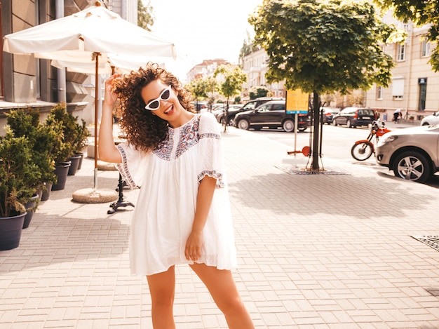 夏の流行に敏感な白いドレスに身を包んだアフロカール髪型と美しい笑顔モデル。