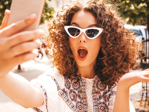 Beautiful smiling model with afro curls hairstyle dressed in summer hipster white dress