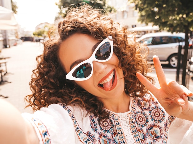 Foto gratuita bello modello sorridente con l'acconciatura di riccioli afro vestito in abito bianco hipster estate.