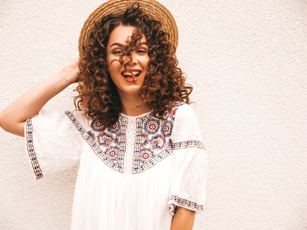 Beautiful smiling model with afro curls hairstyle dressed in summer hipster white dress.