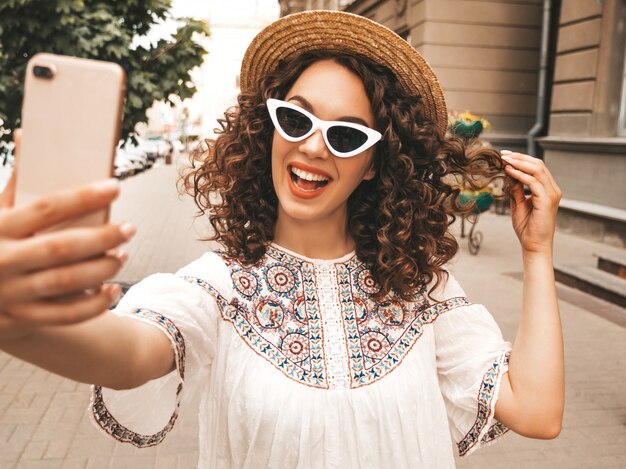 Beautiful smiling model with afro curls hairstyle dressed in summer hipster white dress.