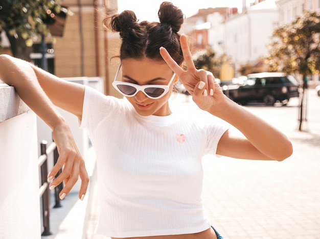 Free photo beautiful smiling model with horns hairstyle dressed in summer hipster jacket jeans clothes.sexy carefree girl posing in the street.trendy funny and positive woman having fun in sunglasses