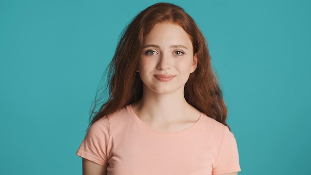 Beautiful smiling redhead girl intently looking in camera over colorful background