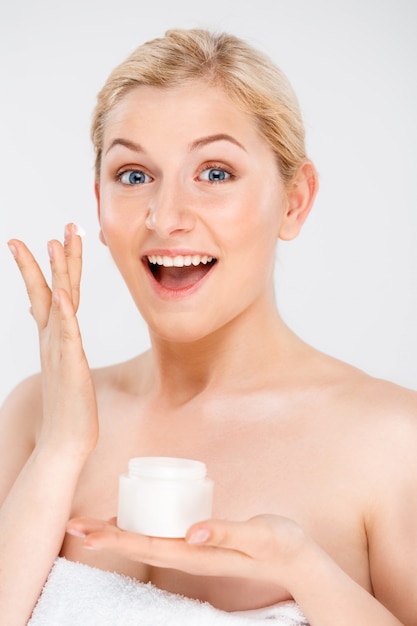 Beautiful smiling woman apply facial cream