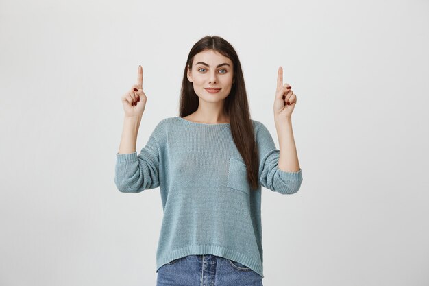 Beautiful smiling woman showing promo, pointing up