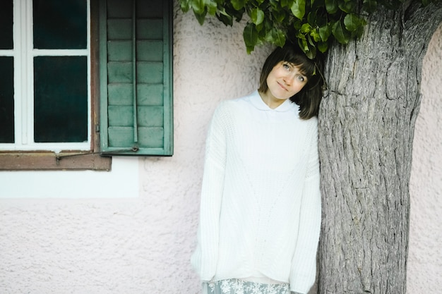 Beautiful smiling woman stands by the tree