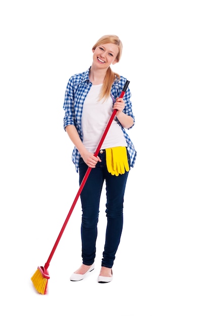 Beautiful and smiling woman sweeping the floor