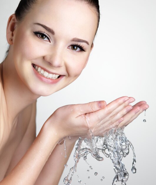 Beautiful smiling woman washing her face with water