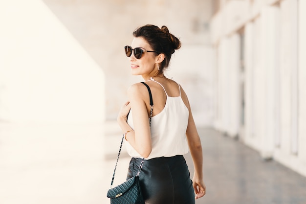 Beautiful smiling young woman in sunglasses looking away over th