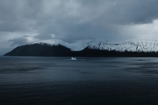 Foto gratuita belle montagne innevate con un lago e un cielo nuvoloso scuro