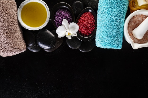 Free photo beautiful spa set spa products with essential oils, soap, towel, spa sea salt on dark wet background. horizontal with copy space.