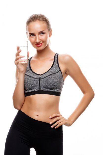 Beautiful sportive woman posing, holding glass of water 