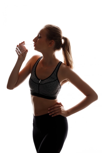 Beautiful sportive woman posing, holding glass of water 
