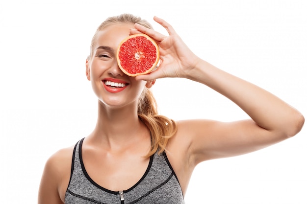 Beautiful sportive woman posing, holding grapefruit 