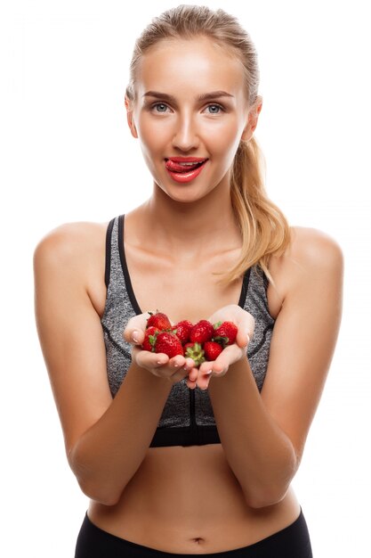 Beautiful sportive woman posing, holding strawberry 