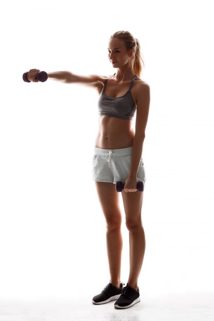 Beautiful sportive woman training with dumbbells 