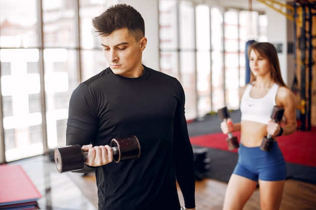 A beautiful sports couple is engaged in a gym