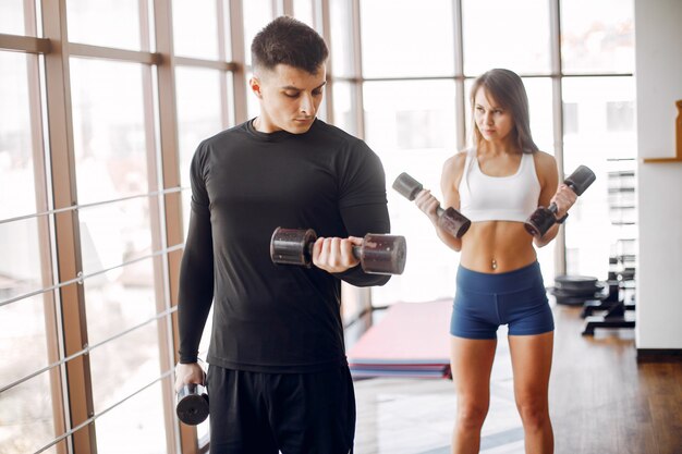 A beautiful sports couple is engaged in a gym