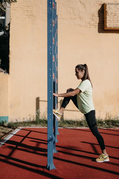 ウォールバーの近くでアクティブウェアトレーニングの美しいスポーティな女性