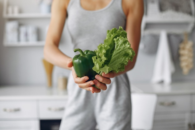 Beautiful and sporty woman in a kitchen with vegetables